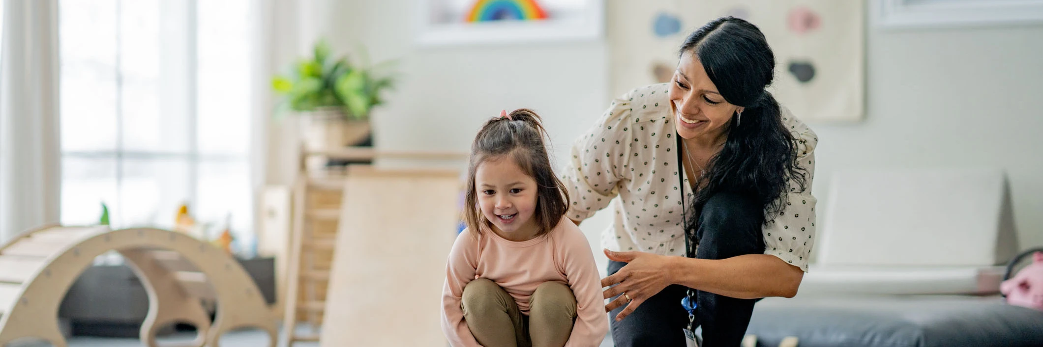 A female Physiotherapist works with a young girl on her balancing during a therapy session.  She is supporting and aiding the young girl as they work together.